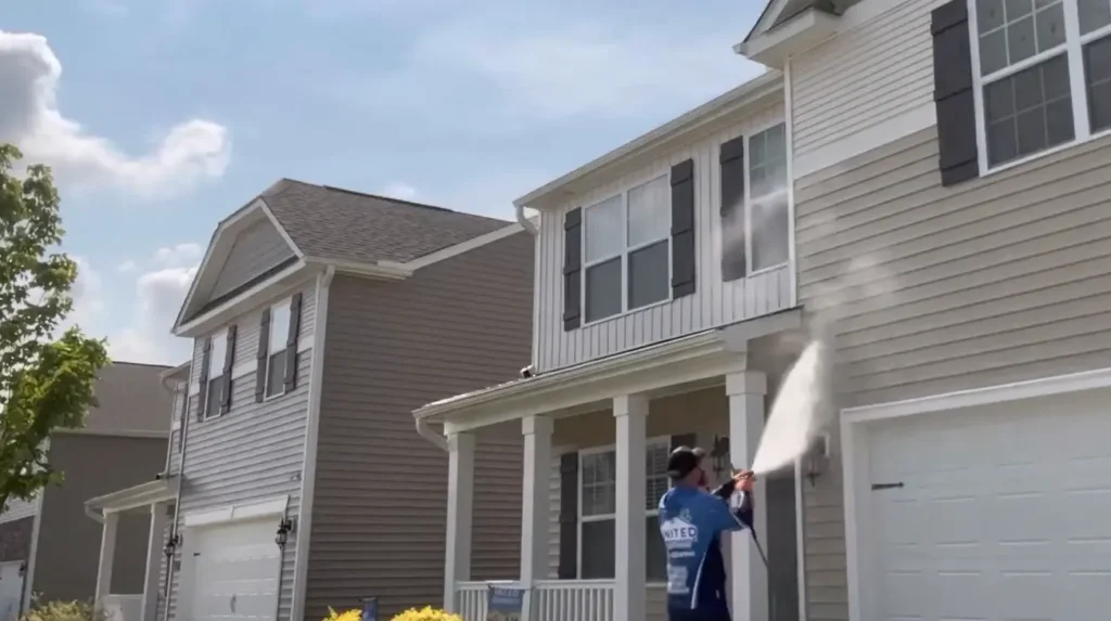 Technician pressure washing a house porch and garage exterior in Jacksonville, FL