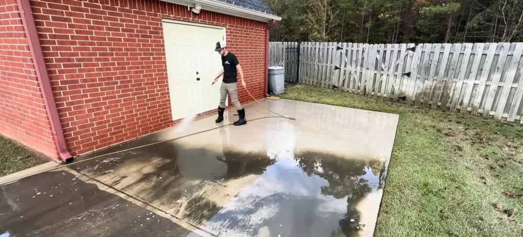 Pressure washing a concrete patio floor behind a home in Jacksonville, FL