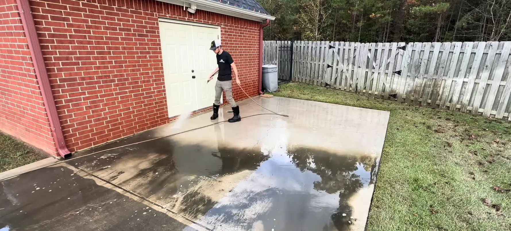 Pressure washing a concrete patio floor behind a home in Jacksonville, FL